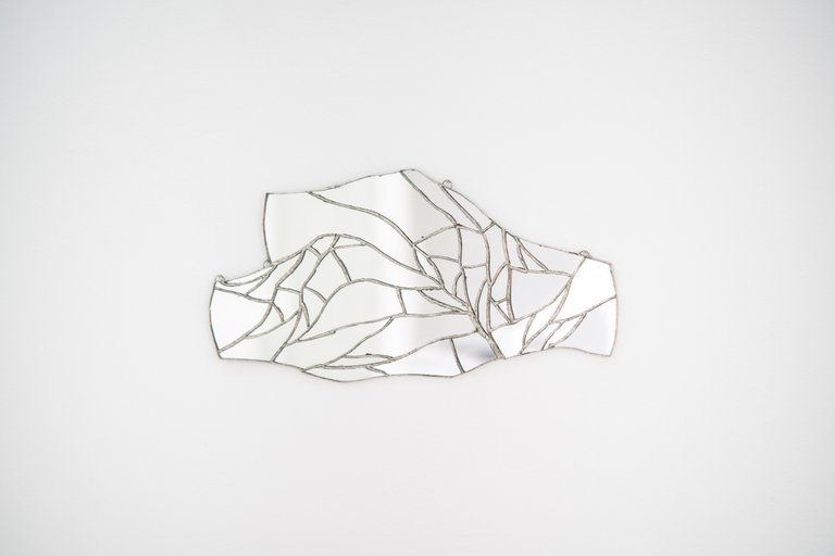 Two hands holding another by Eden Dodd, 2022, mirror, silver alloy