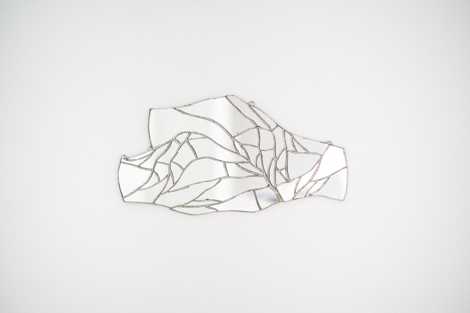 Two hands holding another by Eden Dodd, 2022, mirror, silver alloy
